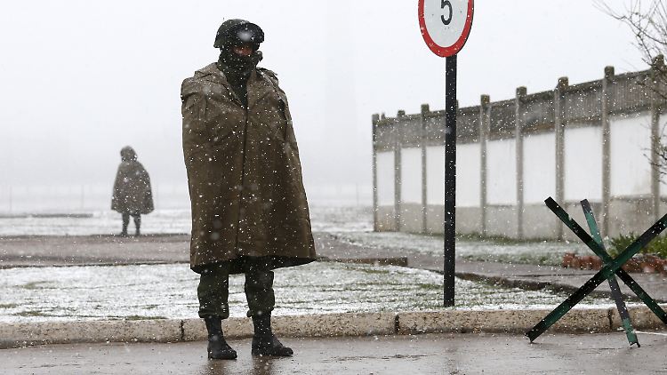 Vor einer Militärbasis in der Ukraine stehen bewaffnete Kräfte. Vermutlich handelt es sich um Russen.