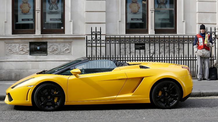 Ein Mann verkauft im Londoner Stadtteil Covent Garden neben einem Lamborghini die Obdachlosenzeitung "Big Issue".