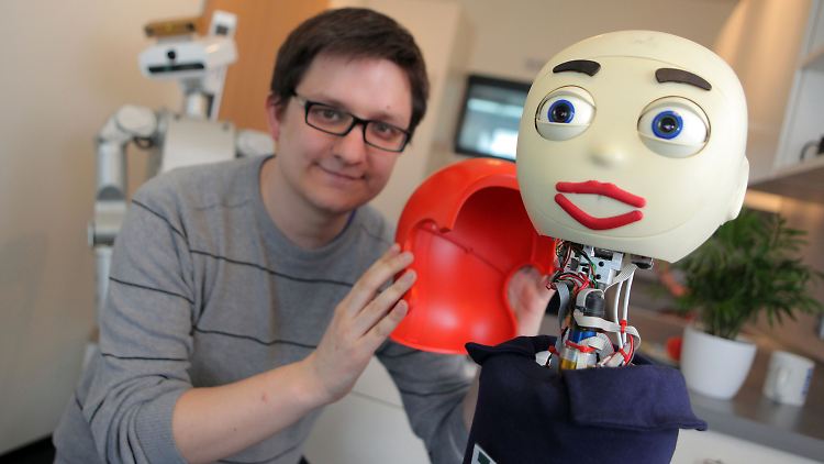 Andreas Kipp von der Uni Bielefeld verpasst Roboter "Flobi" eine rote Haartracht.