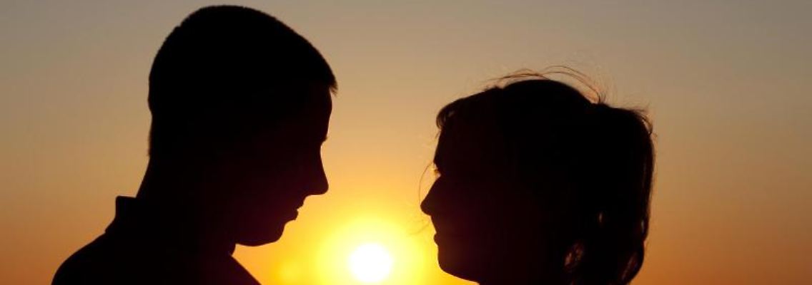 Ein Paar steht bei Sonnenuntergang am Ostseestrand von Warnemünde. Foto: Arno Burgi/Symbol