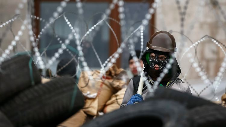 Ein pro-russischer Demonstrant steht hinter einer Barrikade, die um die Regionalverwaltung von Donezk errichtet wurde.