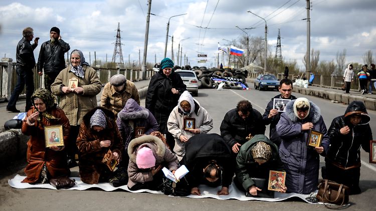 Frauen beten an einer Straße in Slawjansk. Im Hintergrund ist eine Straßensperre von sogenannten Selbstverteidigungskräften zu sehen.