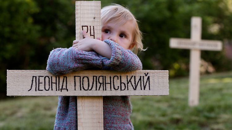 Ein Kind umarmt in Prag eines der  Holzkreuze für die Todesopfer auf dem Maidan. Bei den Protesten in Kiew waren im Februar mehr als 100 Menschen gestorben.