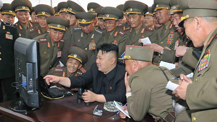 Nordkoreas Machthaber Kim Jung Un und seine Militärs vor einem Computer.