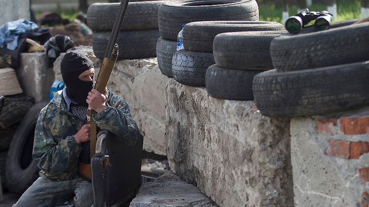 Ein Separatist beobachtet die Straße hinter einem Checkpoint vor Slawjansk. Am Morgen soll die ukranische Armee eine Offensive zur Rückeroberung der Stadt begonnen haben.