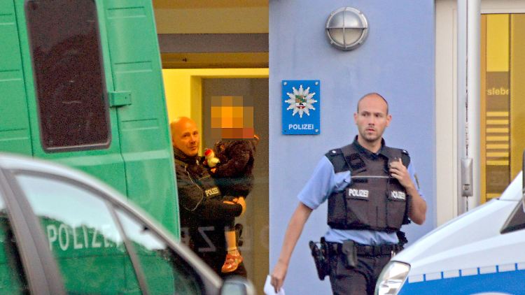 Ein Polizist bringt das Kind in Sicherheit, das mittlerweile wieder bei seinem Vater ist.