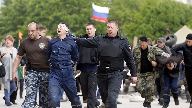 Separatisten führen vor einem besetzten Verwaltungsgebäude in Donetsk unbekannte Männer ab.