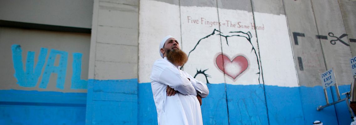 Palästinenser vor einer Grenzwand zu israelischem Gebiet in Betlehem.