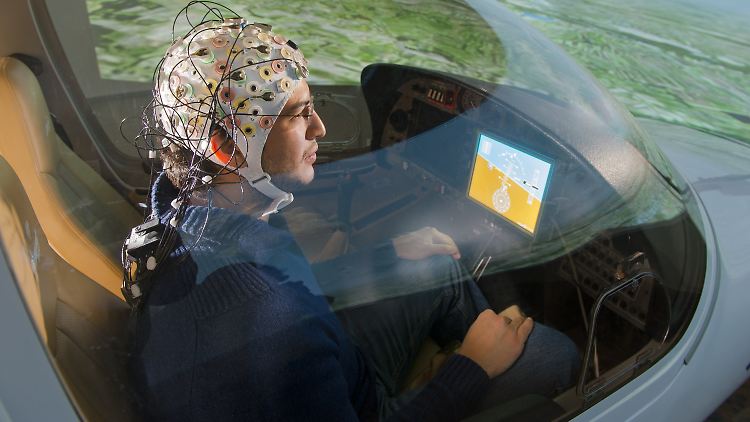Guillermo Falconi sitzt am Lehrstuhl für Flugsystemdynamik in Garching bei München mit einer EEG-Kappe im Flugsimulator zum hirngesteuerten Fliegen.