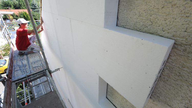 Ein Arbeiter befestigt Dämm-Platten an einer Hausfassade.