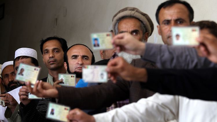 Männer zeigen in einem Wahllokal in Kabul ihre Ausweise.