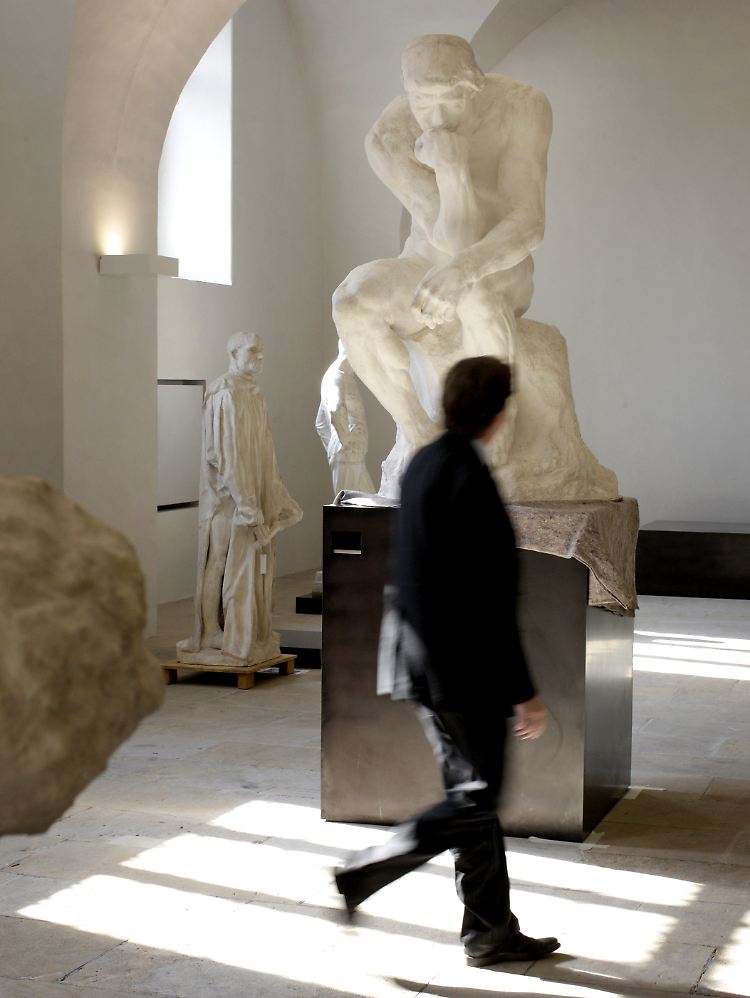 Ein Mann geht an der Skulptur "Der Denker" von Auguste Rodin in der Skulpturenhalle im Dresdner Albertinum vorbei.