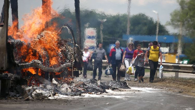 Alltag in der Ostukraine: Ein brennendes Wrack auf der Straße.