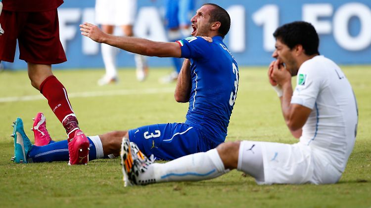 Kurz nach dem Biss: Suárez hält sich mit schmerzverzerrtem Gesicht die Zähne, Chiellini protestiert in Richtung Schiedsrichter.