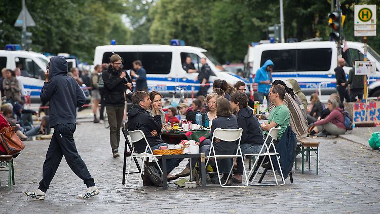 Anwohner haben aus der Not eine Tugend gemacht und frühstücken mitten auf der abgesperrten Straße - auch aus Solidarität mit den Flüchtlingen.