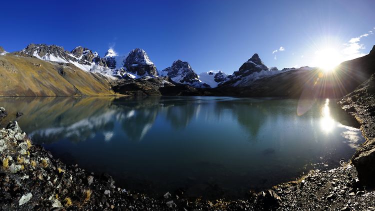 Sonne über einer Lagune mit sich spiegelnden Andenbergen am Bergweiler Tuni bei Laz Paz in Bolivien.