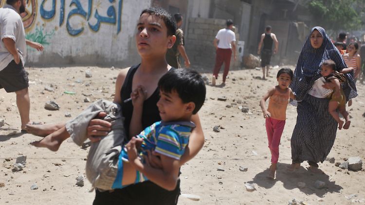 Palästinenser in Gaza-Stadt fliehen mit Kleinkindern auf den Armen vor einem israelischen Luftangriff. 