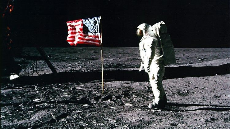 Buzz Aldrin steht neben der Fahne der USA, die er auf dem Mond gehisst hat.