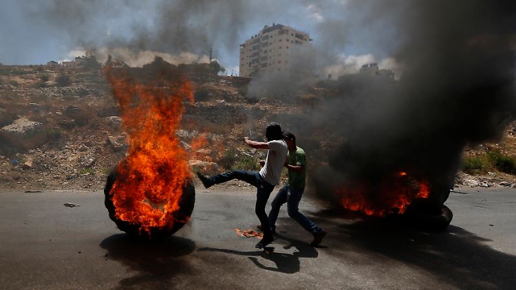 Ein palästinensischer Demonstrant tritt einen brennenden Reifen während der israelischen Offensive.