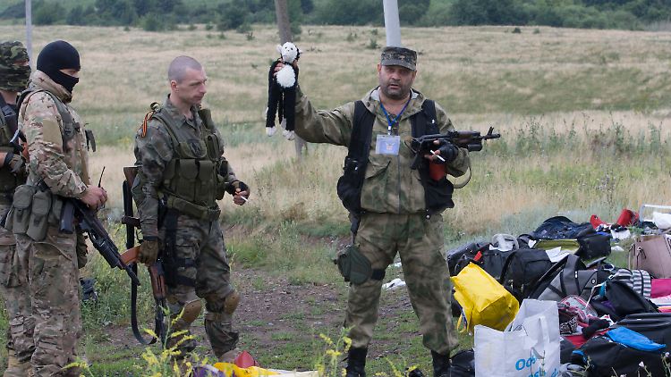 Ein prorussischer Kämpfer an der Absturzstelle zeigt ein Stofftier in die Höhe