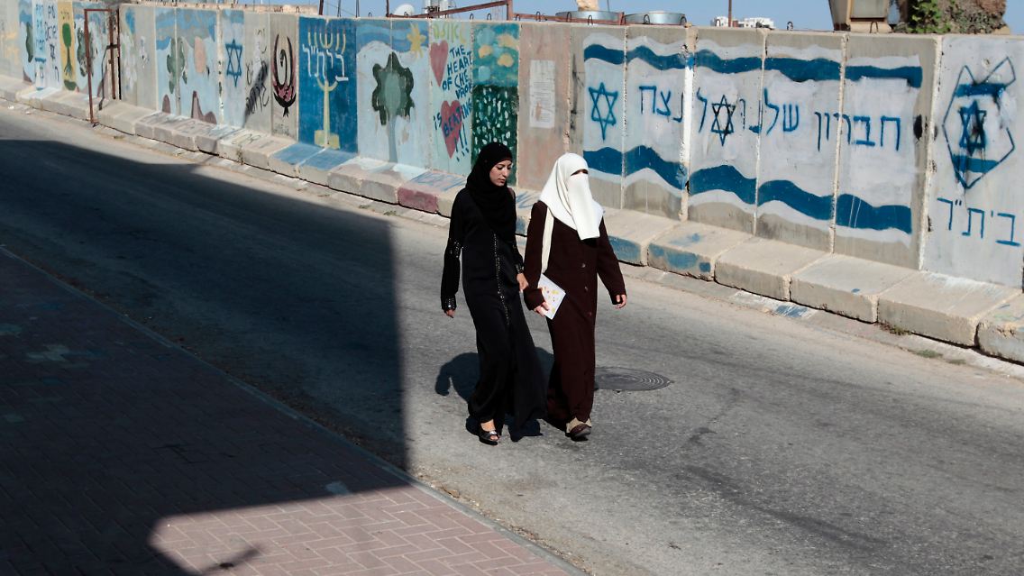 Zwei Palästinenserinnen spazieren in Hebron über die Straße.
