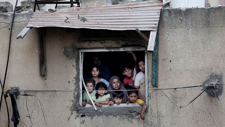 Eine palästinensische Großfamilie beobachtet aus ihrem beschädigten Haus die Suche nach Opfern in Gaza-Stadt.