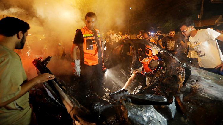 In Gaza Stadt versuchen Palästinenser ein Auto zu löschen, das bei einem israelischen Angriff zerstört wurde.