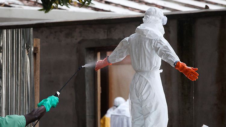 Helfer in Monrovia in Liberia werden mit einem Desinfektionsmittel abgesprüht.