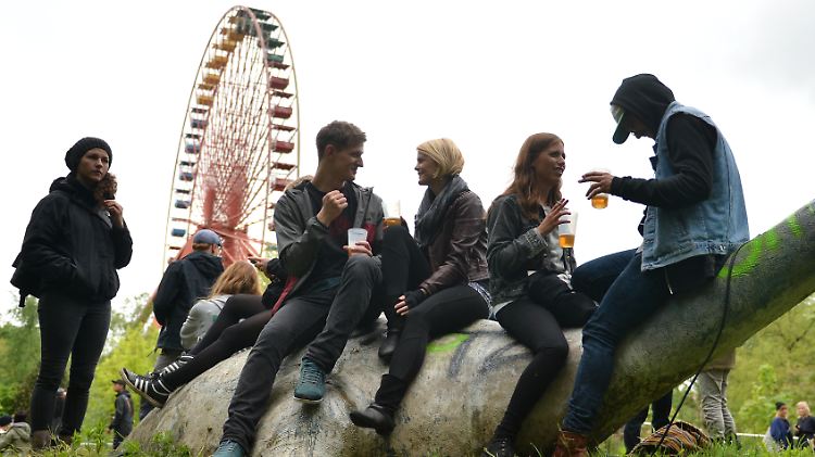 Besucher sitzen im ehemaligen Spreepark in Berlin auf einer Dinosaurier-Figur.