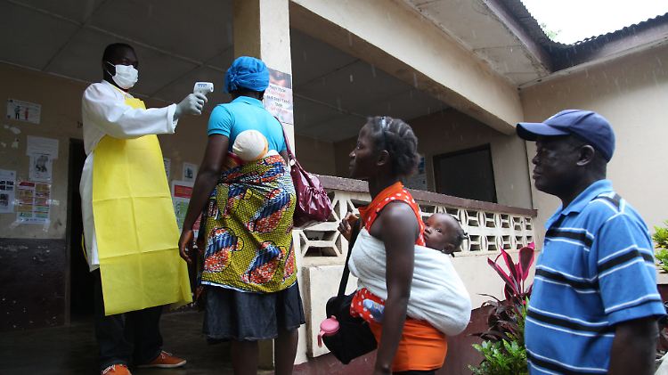 In Liberia stehen Menschen zum Fiebermessen Schlange.