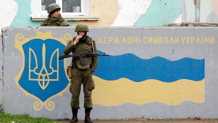 Russische Soldaten im März an einer Wand in Sewastopol, auf die die ukrainische Fahne gemalt ist.