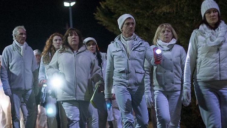 Die weiß gekleideten Übriggebliebenen schweigen und rauchen.