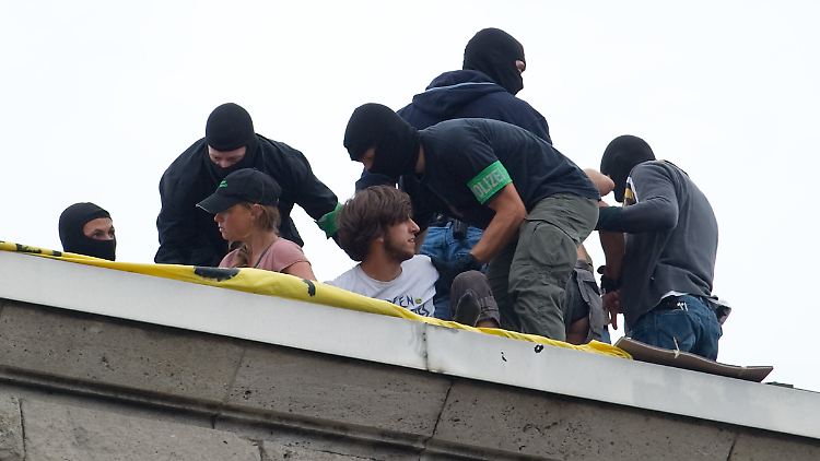 Maskierte Beamte einer Spezialeinheit holen die Demonstranten vom Dach.