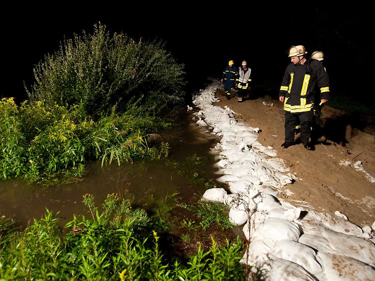 Hält der Damm? Feuerwehrmänner kontrollieren in Rheine, ob das Rückhaltebecken dem Druck widersteht.
