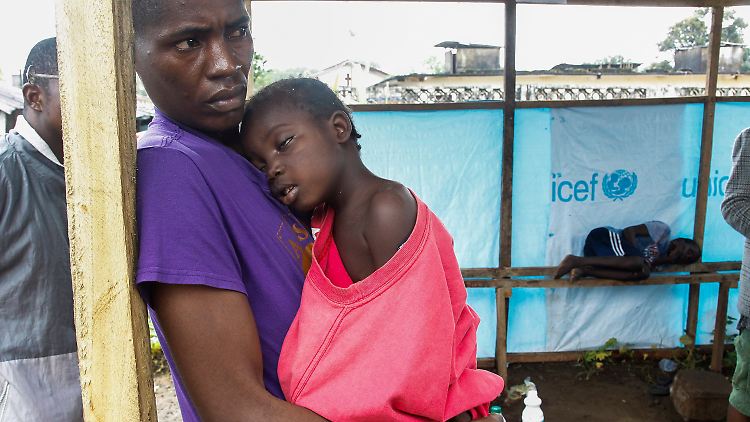 Ein Mann in Liberia stützt seine an Ebola erkrankte Tochter.