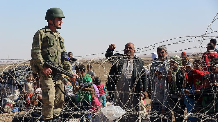 Tausende syrische Kurden warten hinter Stacheldraht auf das Okay der türkischen Grenzsoldaten.