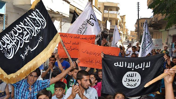 Im syrischen Bürgerkrieg können Dschihadisten zum kleineren Übel werden. Syrer in Maarat al-Numan demonstrieren gegen die Luftangriffe der USA. Sie halten auch Fahnen der Al-Nusra-Front und des IS in die Höhe.