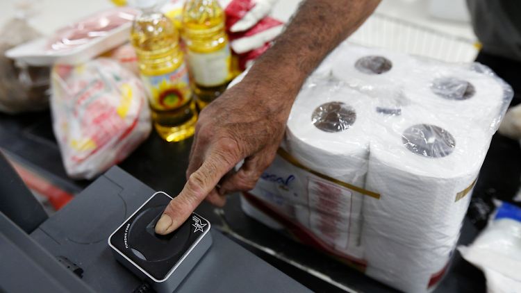 Ein Kunde lässt seinen Fingerabdruck an der Kasse eines staatlichen Supermarktes einscannen. Grund für die Maßnahme sind befürchtete Hamsterkäufe durch verzweifelte Venezuelaner.