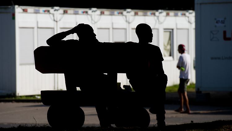 Flüchtlinge sitzen vor Containern in der Landesaufnahmebehörde für Asylsuchende in Braunschweig.