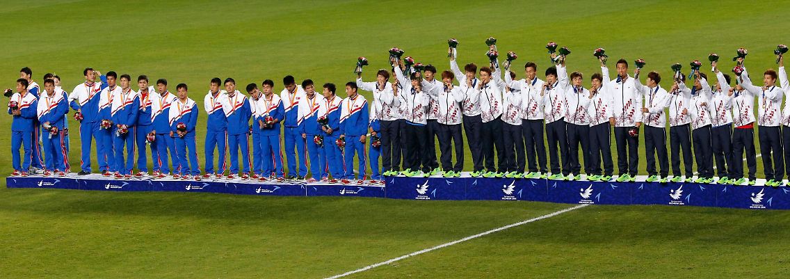 Sieger (rechts) winken mit Blumensträußen, Verlierer tun das nicht - so ist das wenn Süd- und Nordkorea gegeneinander Fußball spielen.
