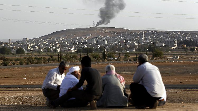 Geflüchtete Syrer beobachten von der türkischen Seite aus, wie schwarzer Rauch auf den Hügeln hinter Kobane aufsteigt.