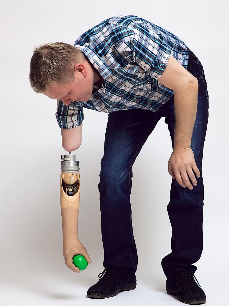 Ein Patient mit einer Neuroprothese hebt einen Gummiball vom Boden auf. Die Prothese funktioniert unabhängig von der Körperhaltung.