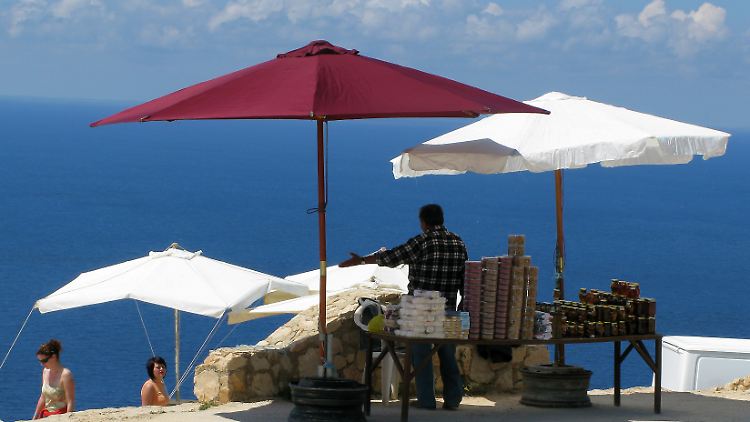 An der Westküste der griechischen Insel Zakynthos bietet ein Händler Touristen seine Waren an.