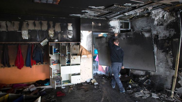 Arbeiter räumen das von dem Brandanschlag schwer beschädigte Zimmer auf.