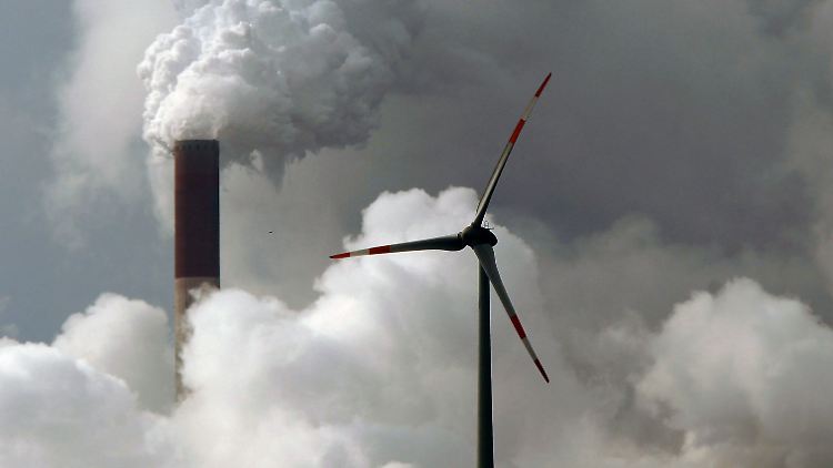 Eine Windturbine dreht sich vor den Schloten des Gelsenkirchener Kohlekraftwerks Scholven.