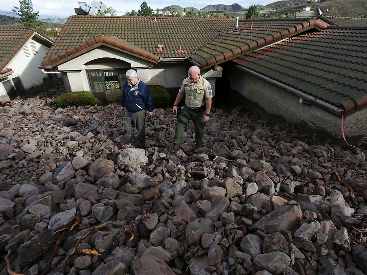 Starke Regenfälle, Sturmböen und tonnenweise loses Geröll: Im Ventura County begutachtet Deputy Joe Gallante mit einem Anwohner, was der Erdrutsch in Camarillo Springs von seinem Garten übrig ließ.