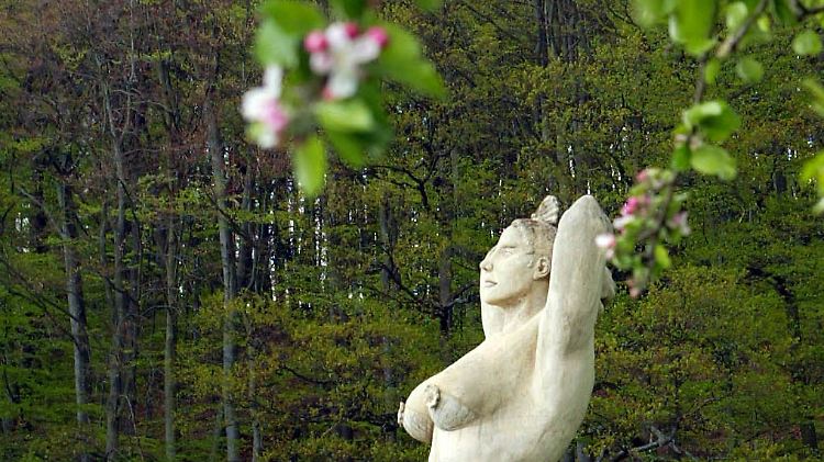 Die üppige "Deutsche Apfelkönigin" des Künstlers Peter Lenk steht auf einer Streuobstwiese und guckt sinnend in die Landschaft von Etzleswenden. 