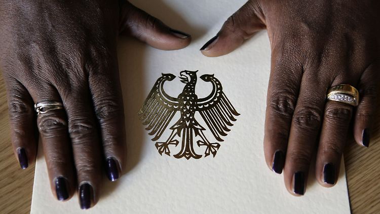 Die Hände einer Schwarzafrikanerin auf einer Einbürgerungsurkunde.