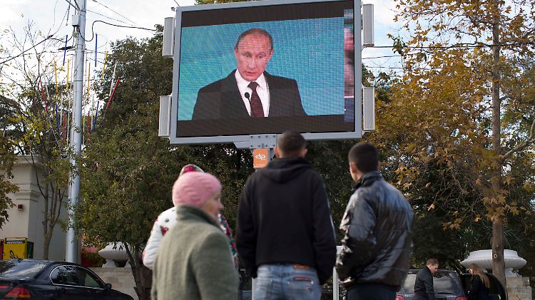 Passanten hören sich eine Putin-Rede auf einer Videoleinwand an - Szene aus Sewastopol. Der Präsident hat viele Freunde auf der Halbinsel, doch die Sanktionen machen dieser und dem ganzen Land zu schaffen.