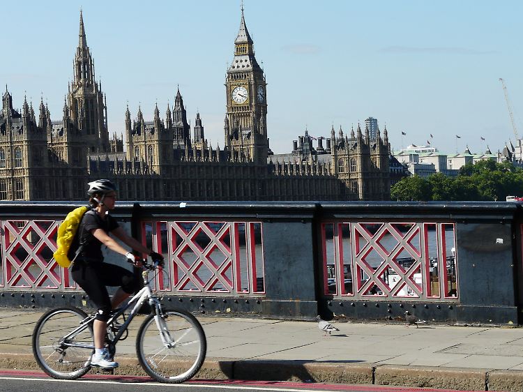 Eine Radlerin fährt in Sichtweite zum Big Ben durch London.